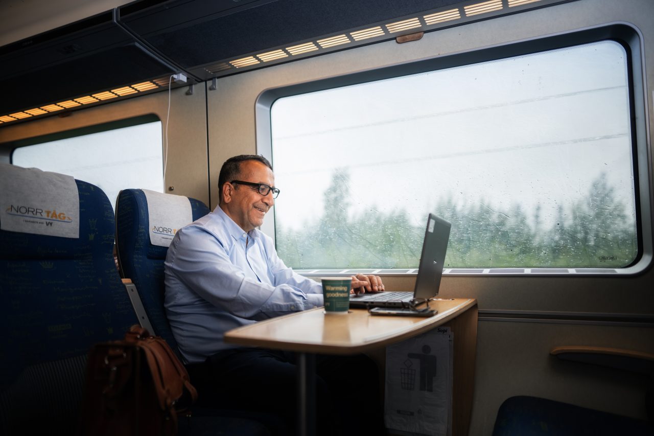 Man sitter med dator och jobbar under resans gång.