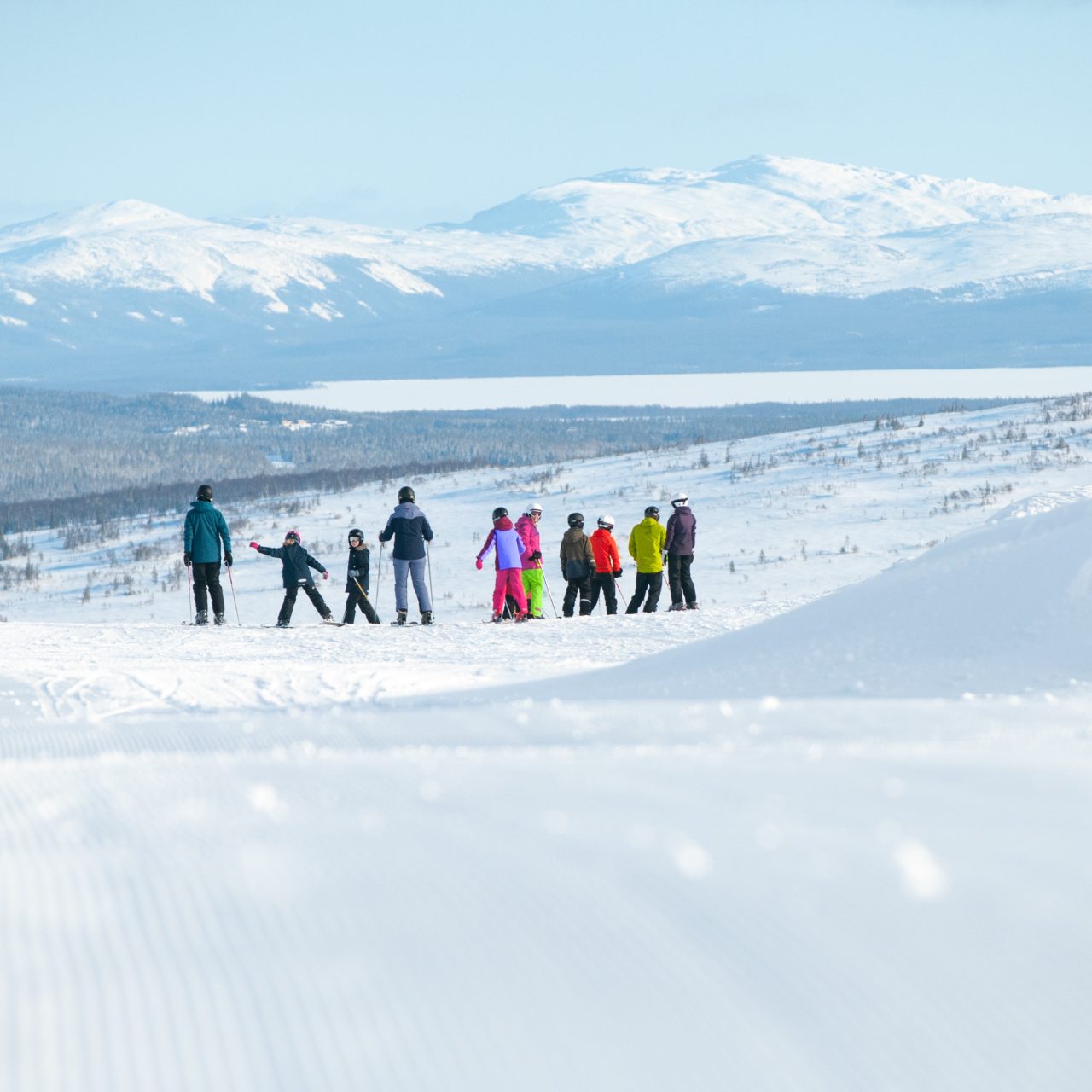 Färgglada skidåkare med fjäll i bakgrund